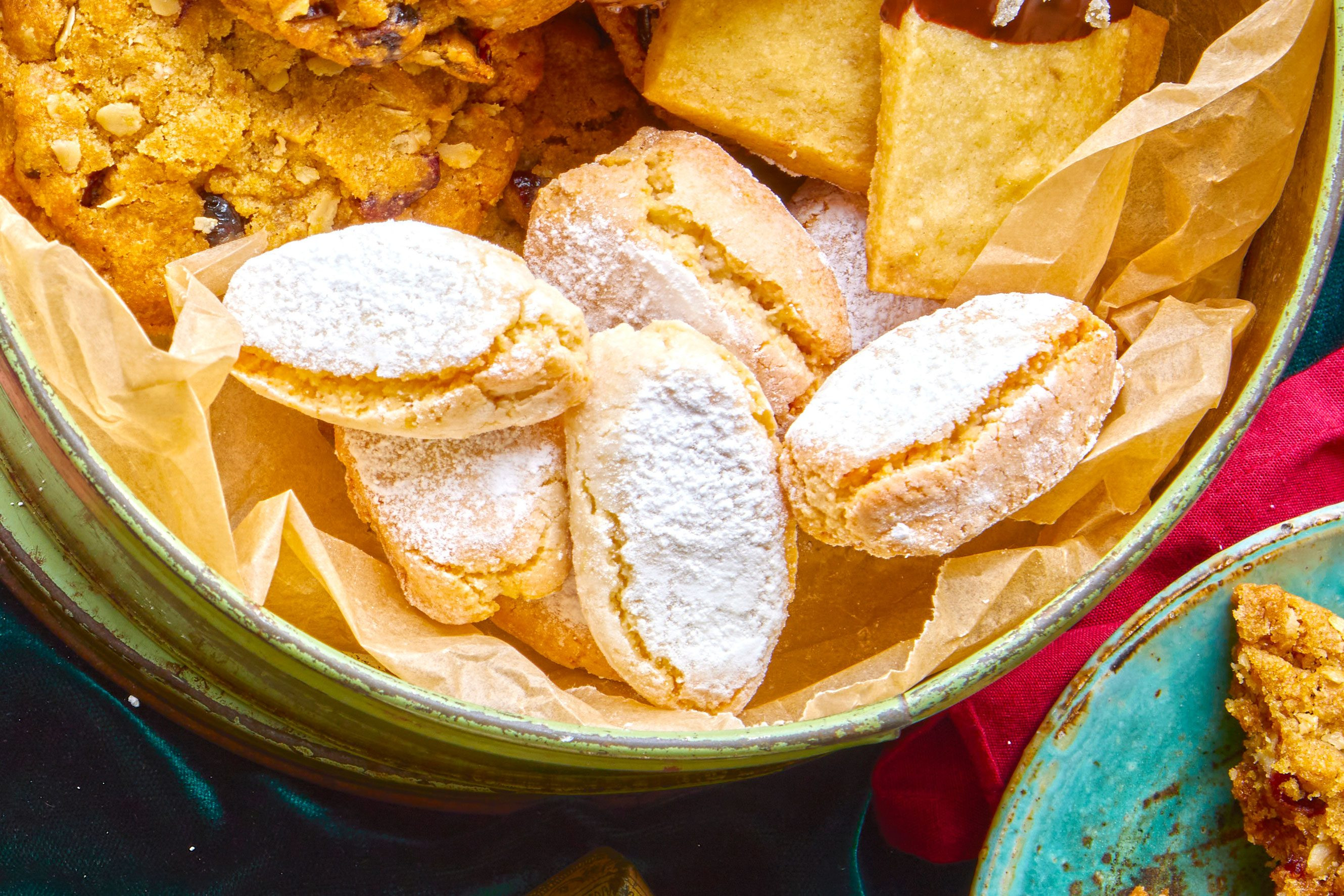 Ricciarelli biscuits dusted with icing sugar in a bowl with other biscuits