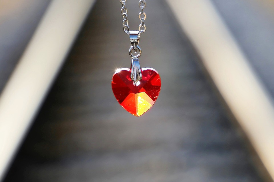 A close-up photo of a red heart pendant on a silver chain