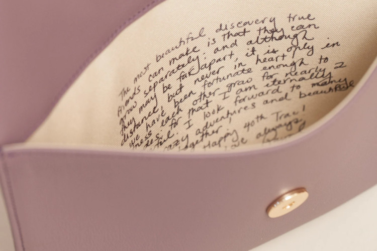 A bridesmaid holding a personalized clutch with a special message inside, showcasing a thoughtful bridesmaid gift.