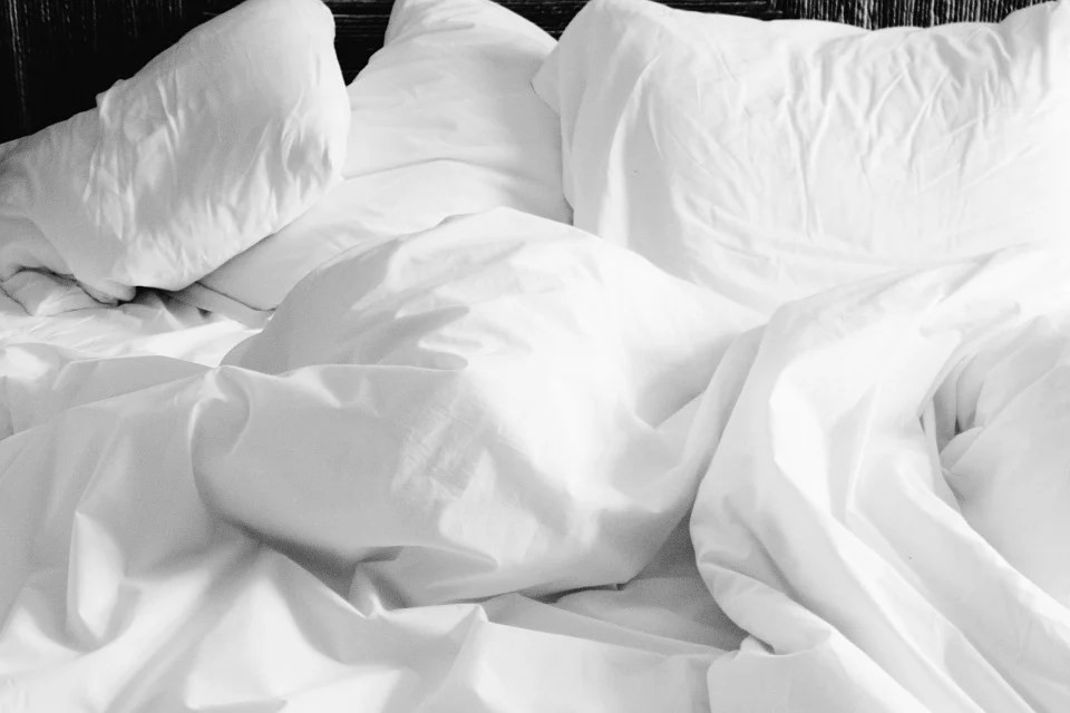 A bed with white linens and pillows
