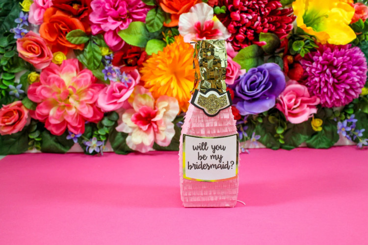 A pink champagne bottle proposal piñata, a fun and unique bridesmaid proposal gift idea.