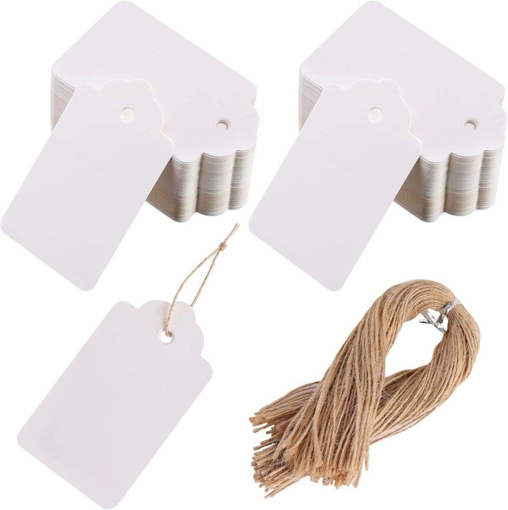 Stacked blank gift tags with a scalloped edge and punched holes, perfect for adding a personalized touch to your gift wrapping, accompanied by a bundle of jute twine, showcasing scalloped edge gift tags for decorative gift packaging.