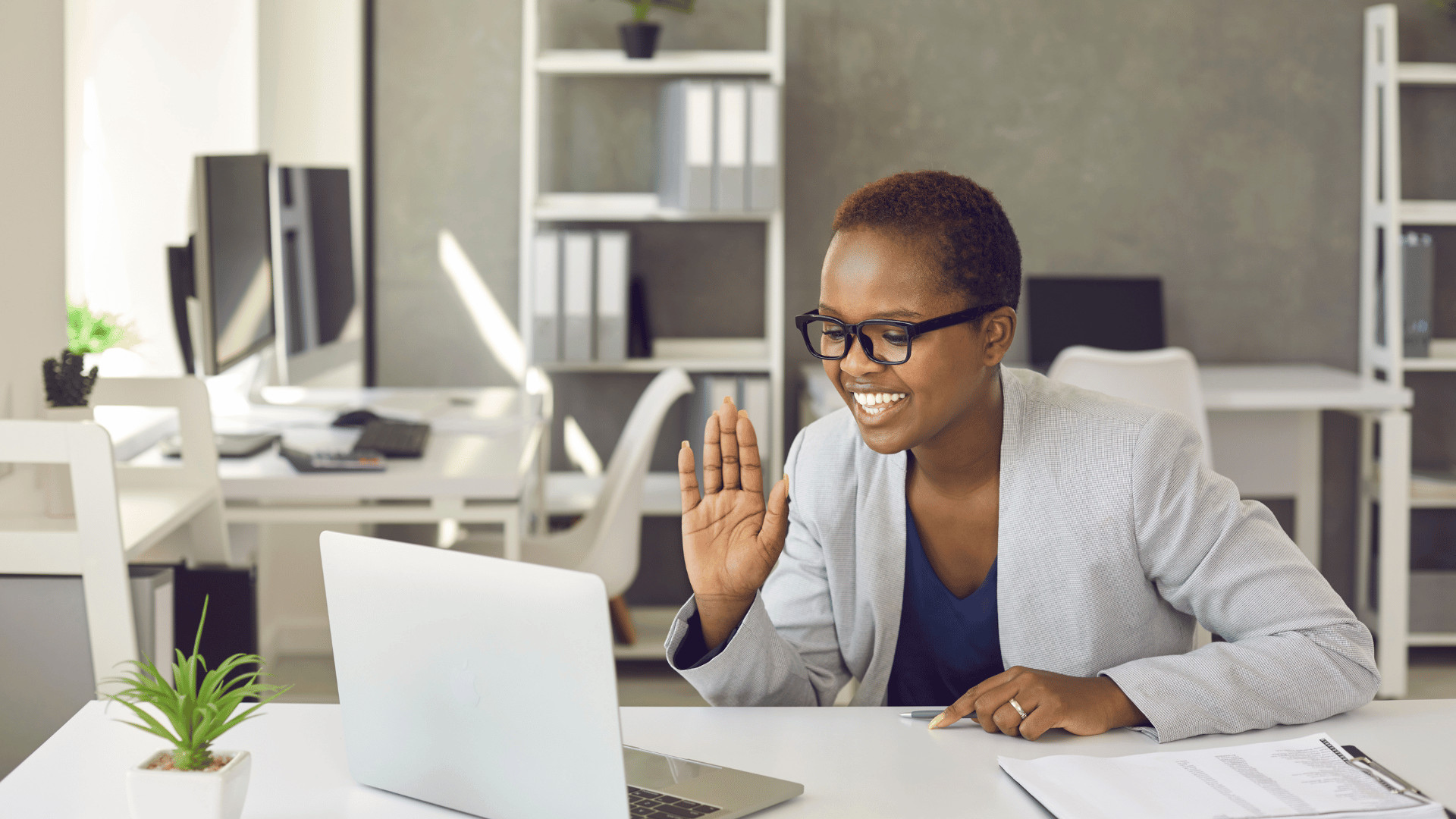 Remote employee waving during a video call, representing gifts for virtual teams