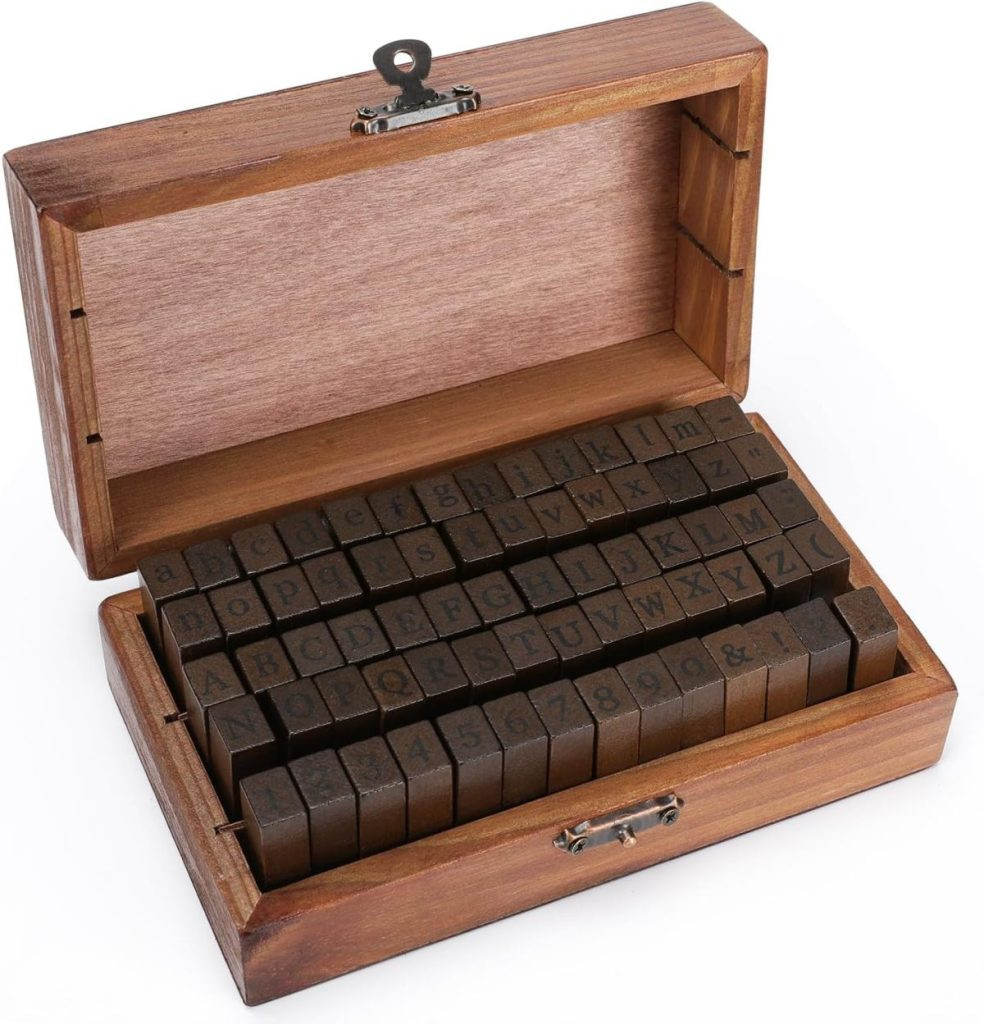 Wooden box containing neatly arranged rubber alphabet stamps and numbers, perfect for adding a personal touch to your gift wrapping. Box is open with stamps visible, presenting alphabet stamp sets for personalized gift tag creation.