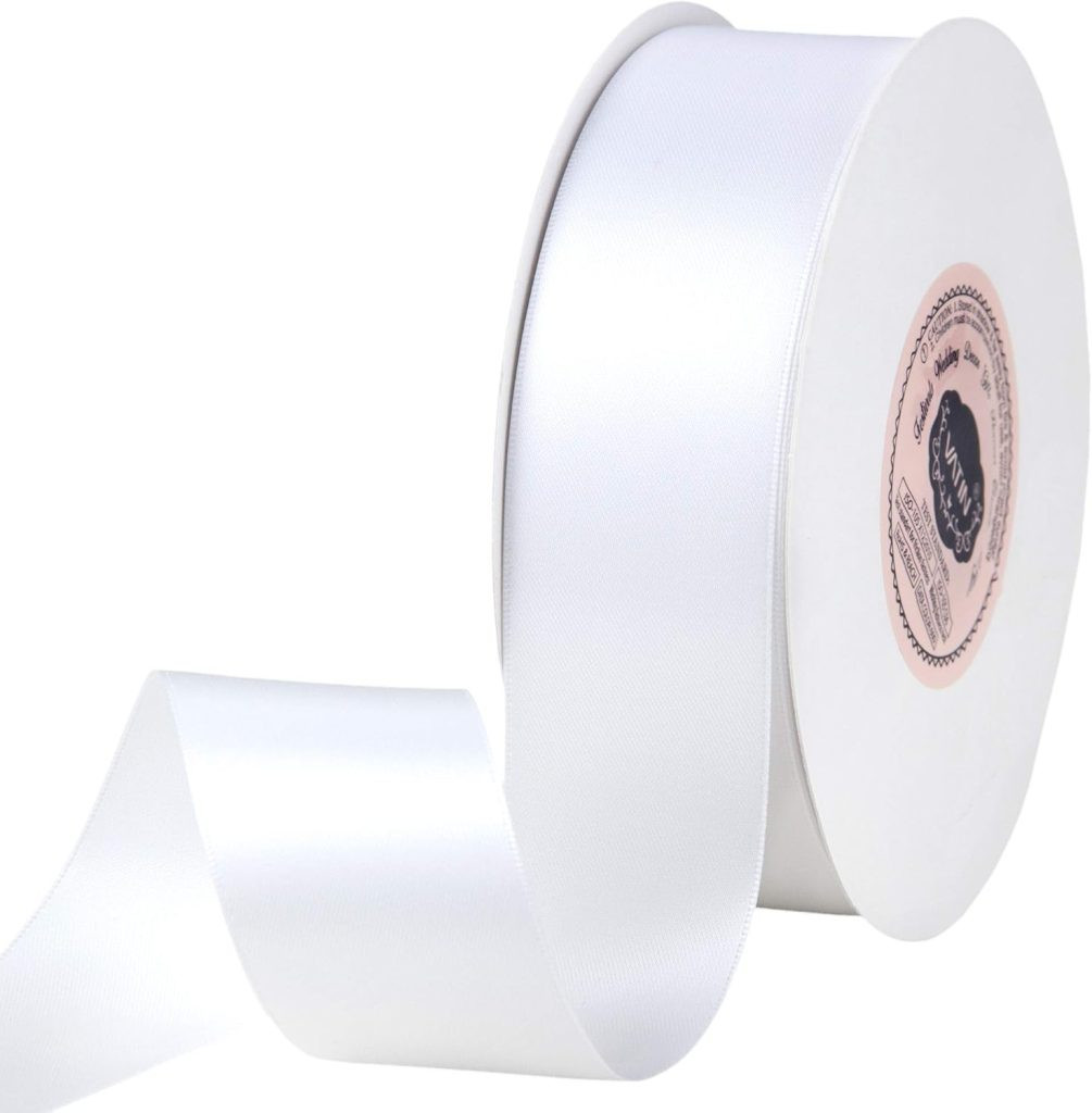 A spool of white satin ribbon with a soft sheen is partially unrolled, perfect for gift wrapping, displaying its smooth texture, showcasing a versatile and elegant ribbon option.