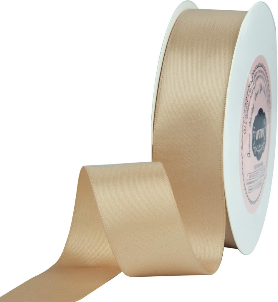 A spool of beige satin ribbon, perfect for gift wrapping, is partially unrolled, offering a neutral and sophisticated ribbon choice.
