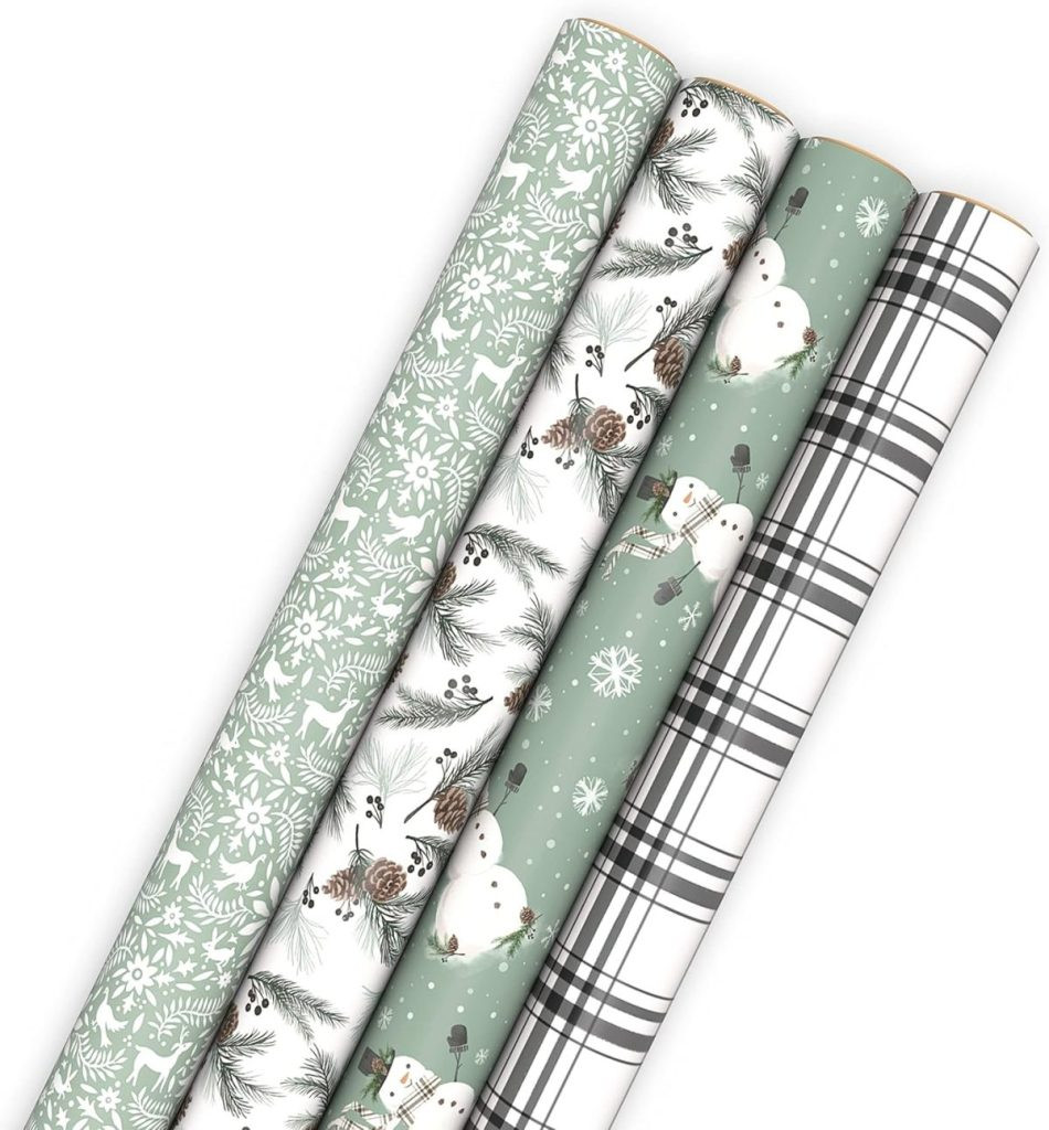 Four rolls of holiday-themed gift wrapping paper with different designs: green with white trees, pine cones, snowmen on green, and black and white plaid, showcasing a range of holiday-inspired gift packaging styles.