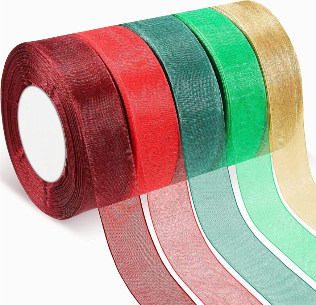 Five rolls of sheer ribbon in maroon, red, green, teal, and gold are elegantly arranged in a row, perfect for adding a touch of flair to gift wrapping, displaying a variety of sheer and colorful ribbon options.