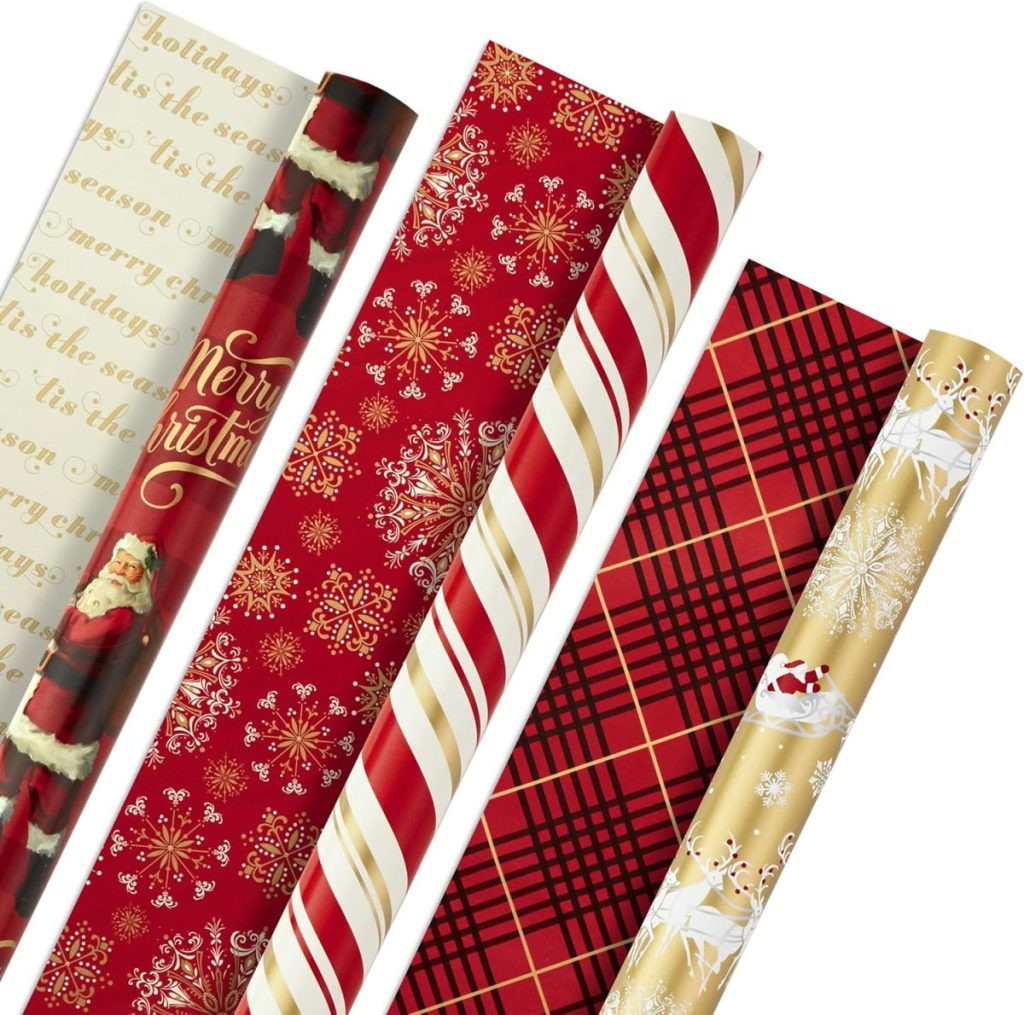 Five rolls of festive gift wrapping paper with Christmas-themed designs, including Santa, text, snowflakes, stripes, plaid, and sleighs, offering classic holiday gift packaging options.