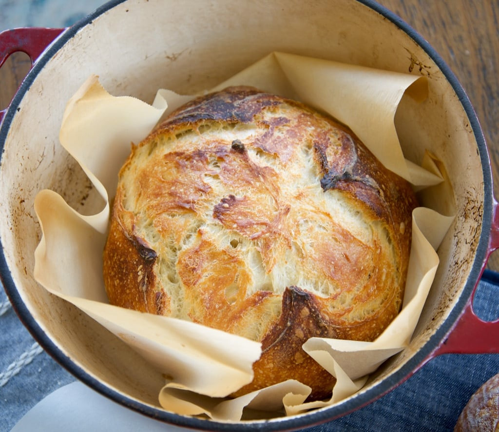 A baked sourdough loaf in a Dutch oven, highlighting the cookware's role in achieving a perfect crust and crumb.