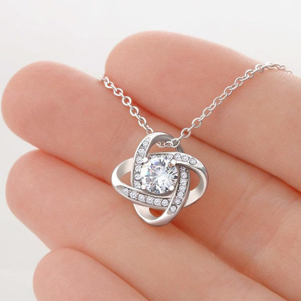 Close-up of a hand gracefully presenting the Love Knot Necklace, an exquisite birthday gift for a wife.
