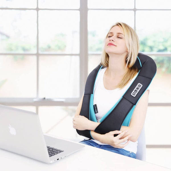 A woman relaxing with a heated neck massager while working on her Macbook, a practical birthday gift for a wife's well-being.
