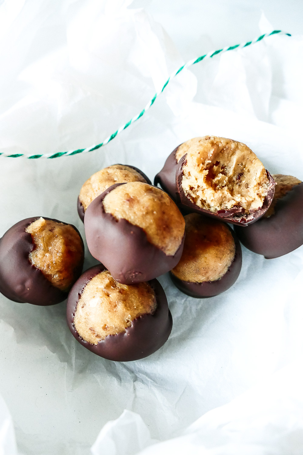 A plate of buckeye candies, showcasing their round shape and peanut butter center dipped in chocolate.