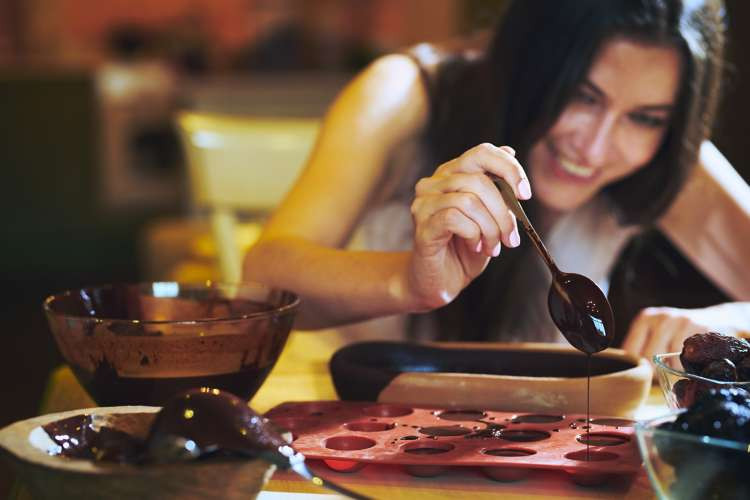 A chocolate making kit with various ingredients, tools, and molds, ready to be used for creating homemade chocolates