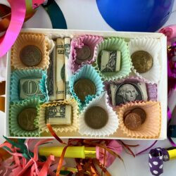 Close-up of a chocolate money box surrounded by party decorations, festive money gift presentation