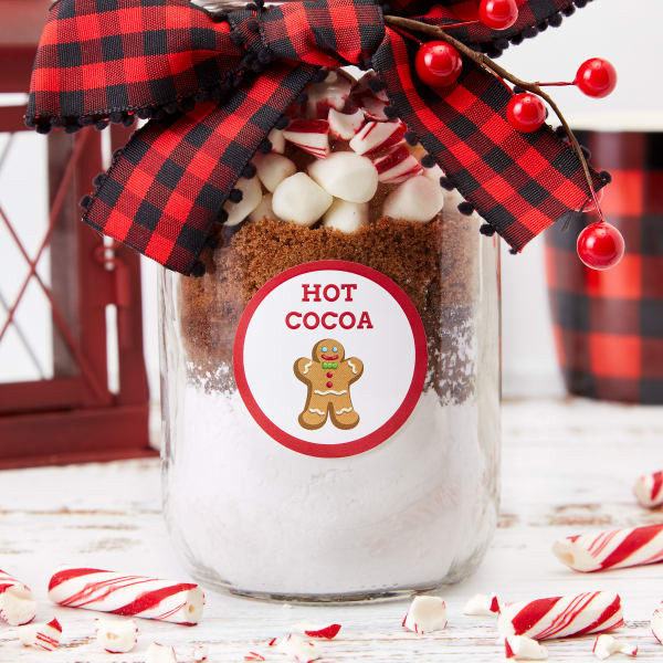 Hot cocoa jar Christmas gift for coworkers made using Avery round label 22807. The label has a cute gingerbread man and reads, 