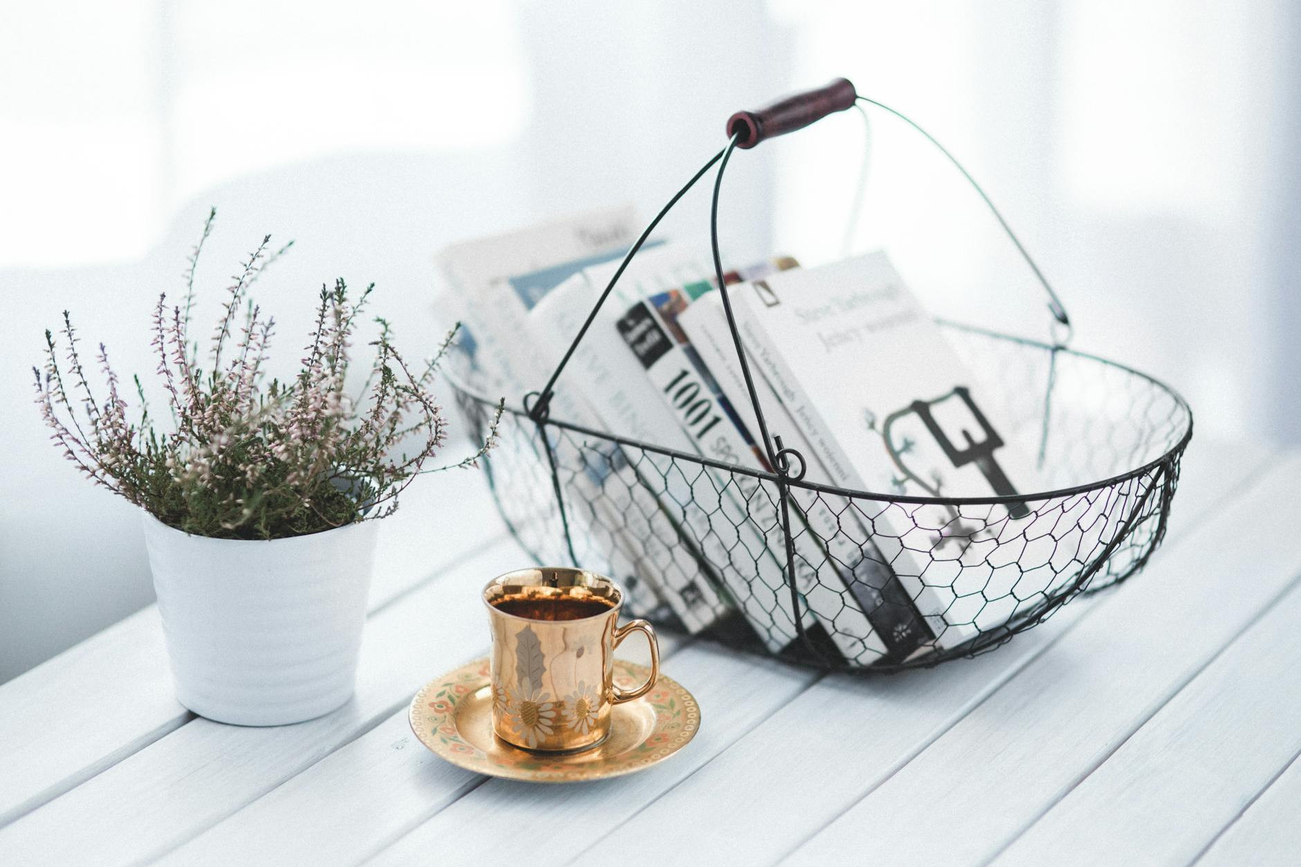 golden cup, plant and basket with coffee table books on a table with white backdrop