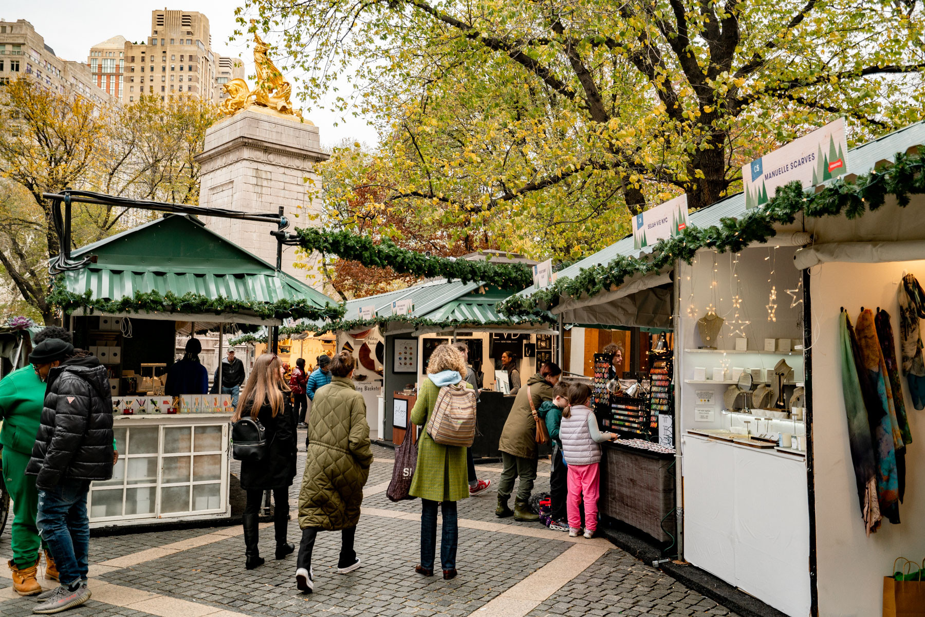 Girls walking through the Columbus Circle Holiday Market near where a mother and a daughter are buying jewelry from a local vendor, best gift shops NYC