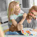 A couple joyfully painting together during a paint and sip class, showcasing a fun and interactive gift idea for married couples.