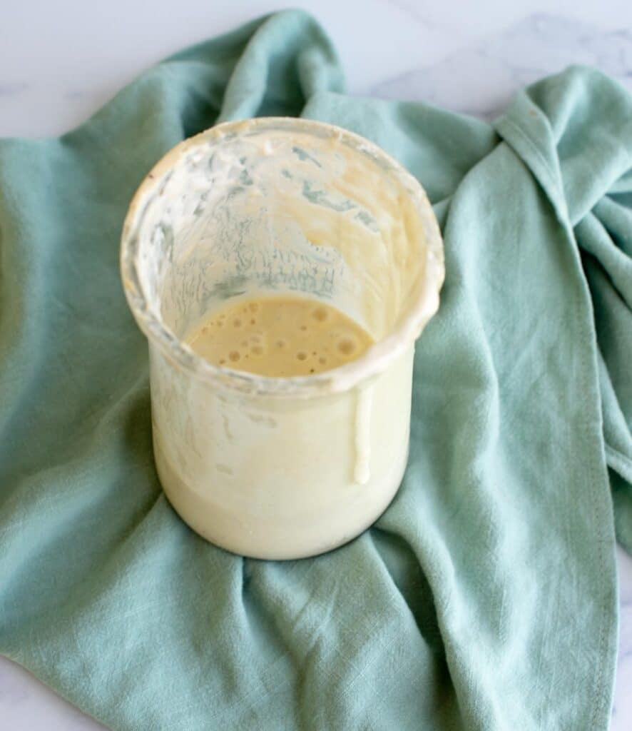 A glass sourdough starter jar with volume markings and a silicone lid, showcasing its practicality and design for starter management.