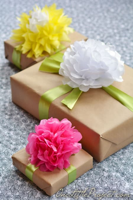 Attaching handmade tissue paper flower to ribbon on wrapped gift