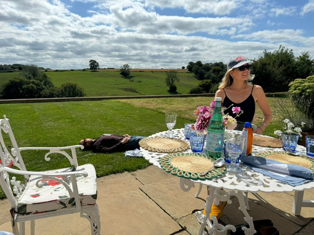 Tarka Russell and other guests at a country house gathering, enjoying food, drinks, and conversation in a relaxed setting