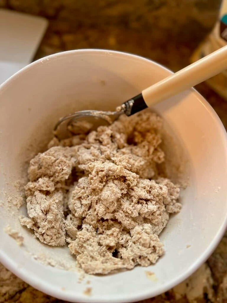 A person using a Danish dough whisk to mix sourdough dough in a bowl, showcasing the whisk's efficient design for combining ingredients.