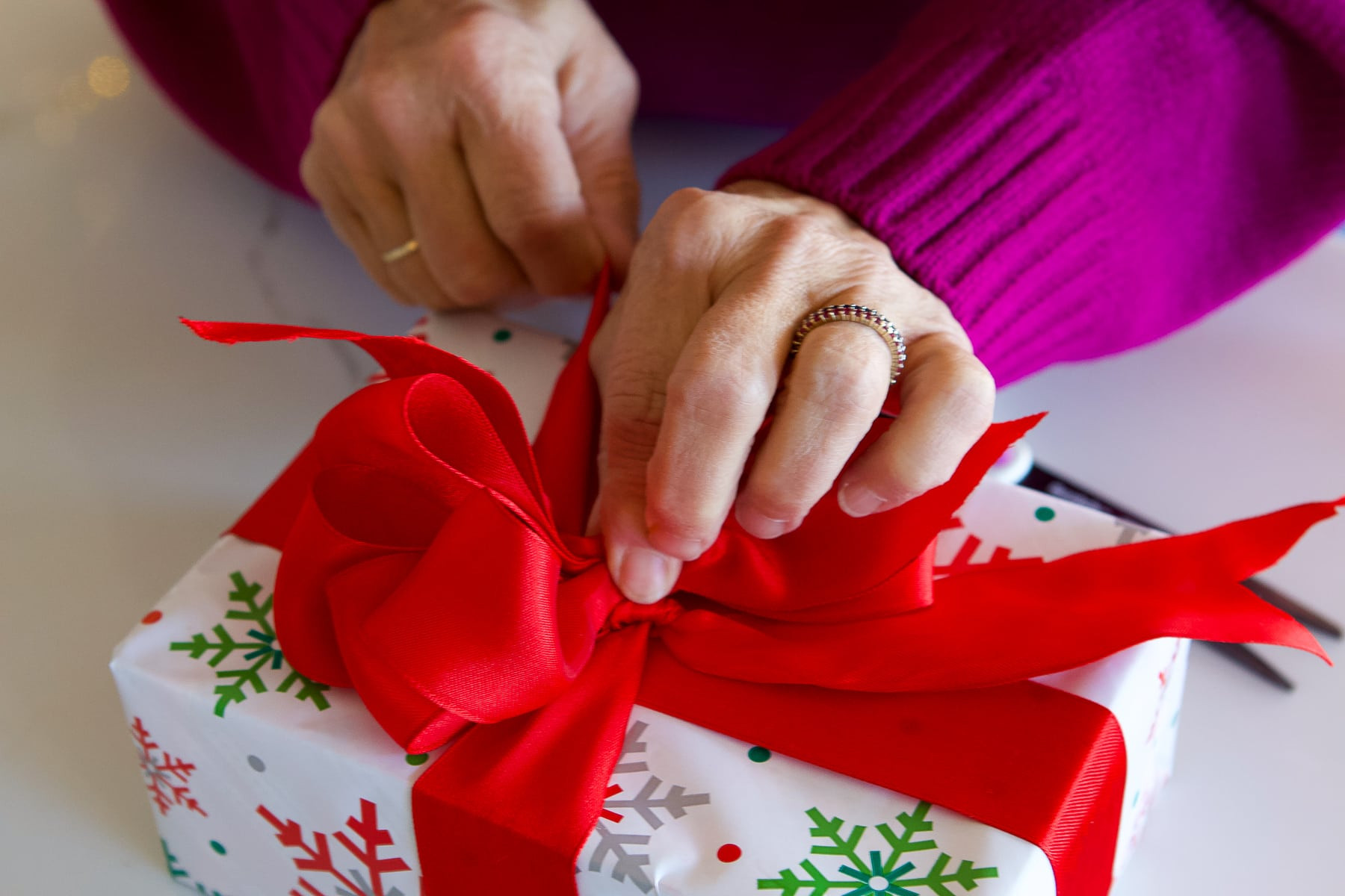 Step 8: Securing the looped bow to the base ribbon by tying a knot