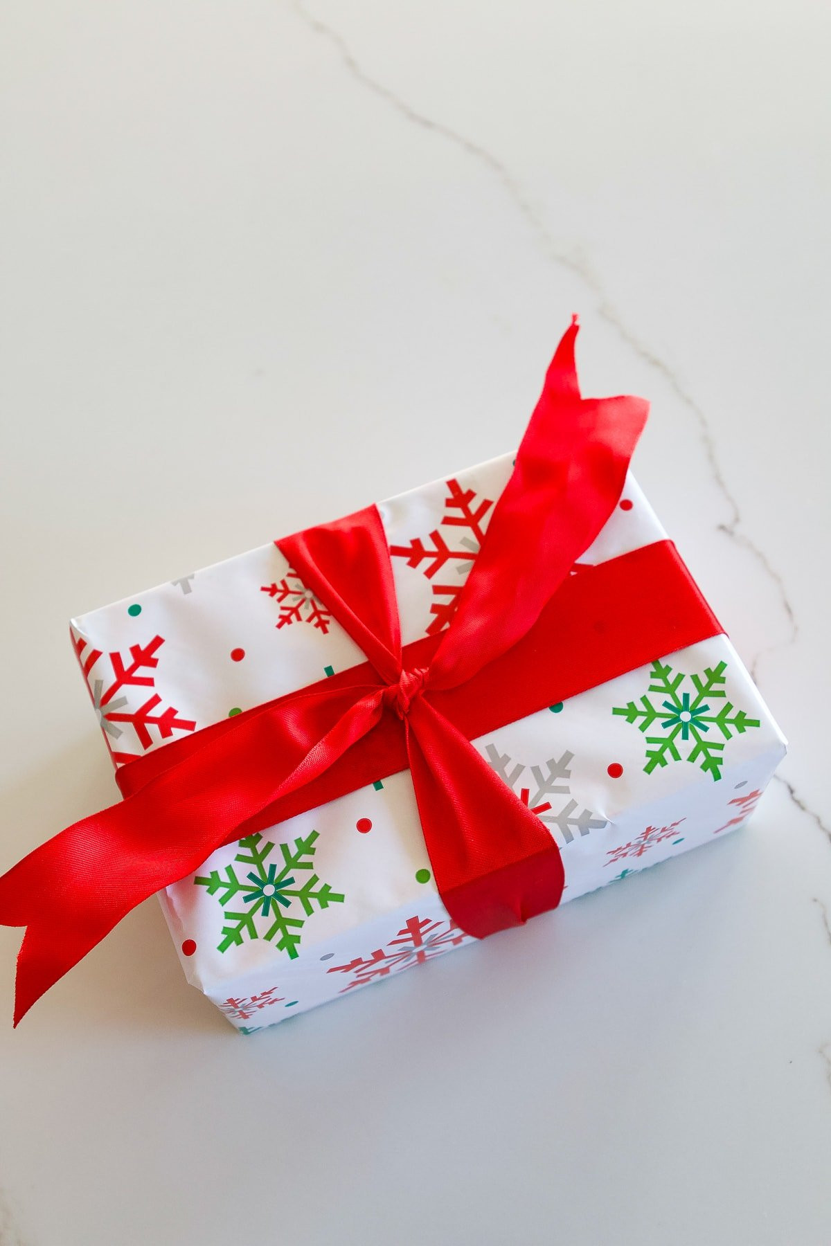 Step 5: Tying the first knot of the base ribbon on top of the gift box