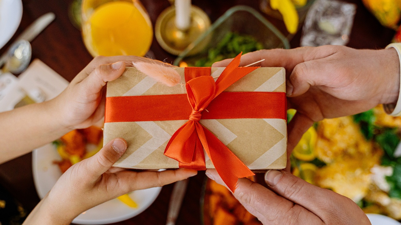 Child receiving a gift, with focus on hands exchanging a wrapped present.