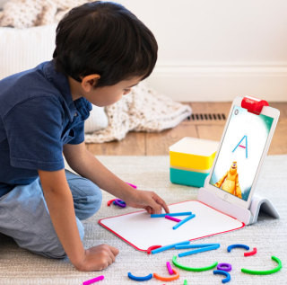 A child happily interacting with the Osmo Little Genius Starter Kit on an iPad, engaging in hands-on learning games.