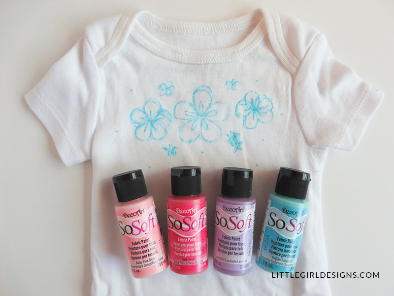 Close-up of painted and embroidered baby onesie design featuring flowers and leaves. Personalized baby gift idea with tutorial.