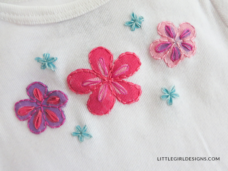 Finished personalized baby gift - painted and embroidered onesie with floral design. Handmade baby shower gift idea.