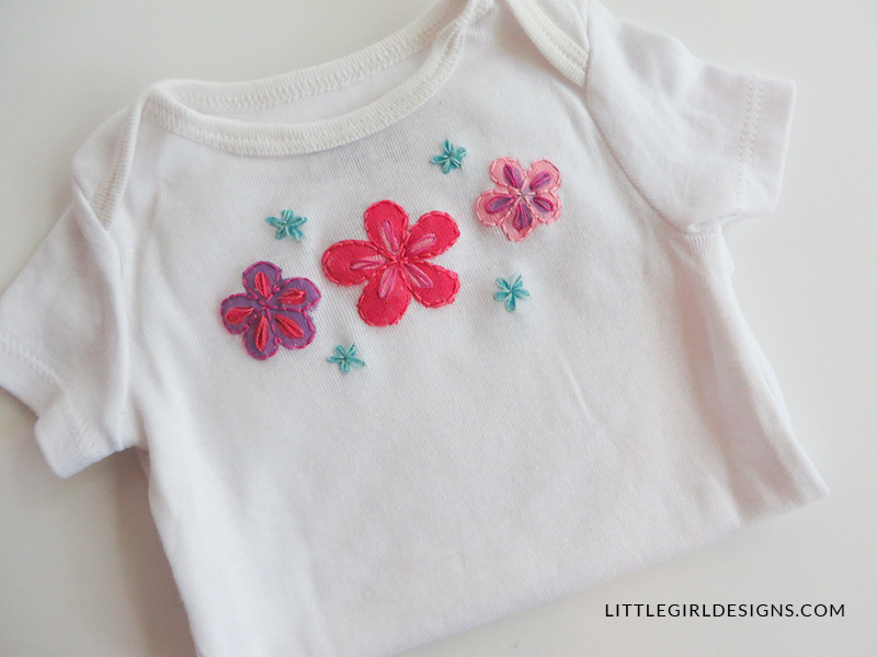 Painted baby onesie drying, showcasing vibrant fabric paint design. Personalized baby gift DIY tutorial step.