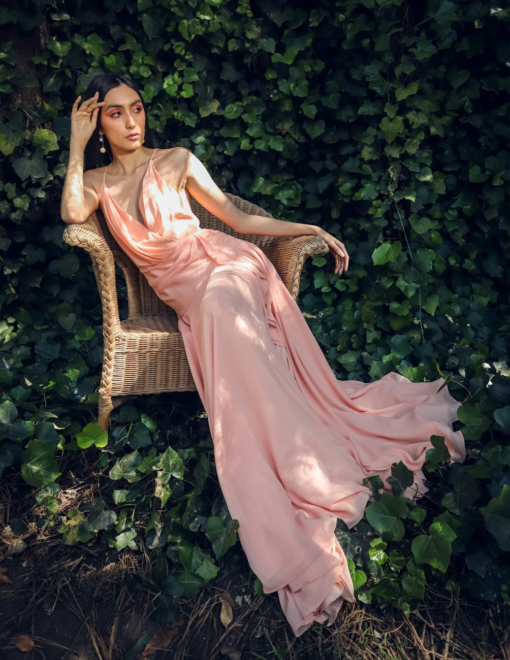 a woman in a pink dress sitting on the background of green ivy, representing a garden set as a gift idea for mom
