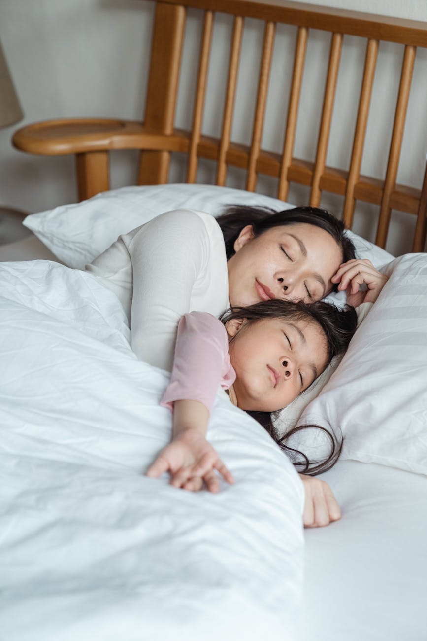 photo of woman and girl lying on bed sleeping