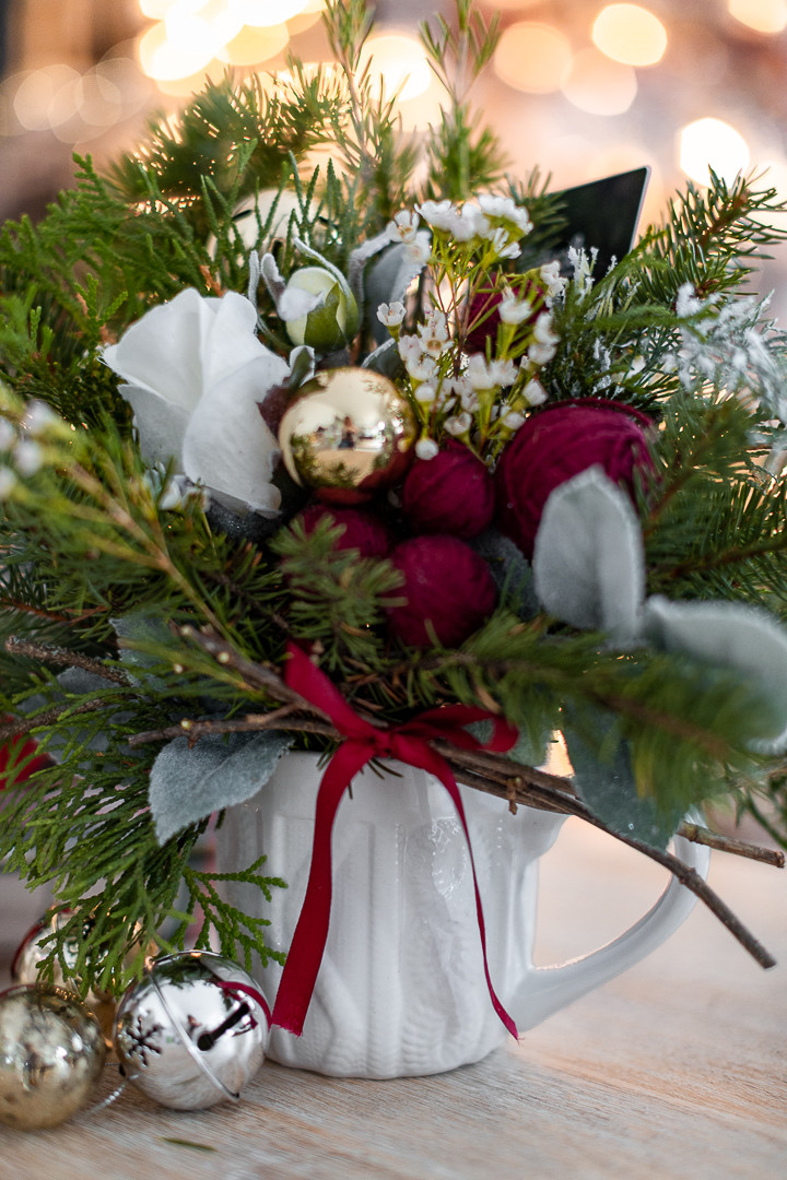 A knitted mug from the Dollar Store used as a container for a small Christmas flower arrangement gift, demonstrating budget-friendly small Christmas gift ideas