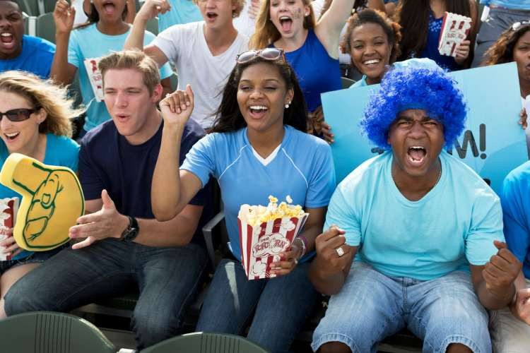 A couple enthusiastically cheering and high-fiving at a sports game, highlighting season tickets as an exciting gift for married couples.