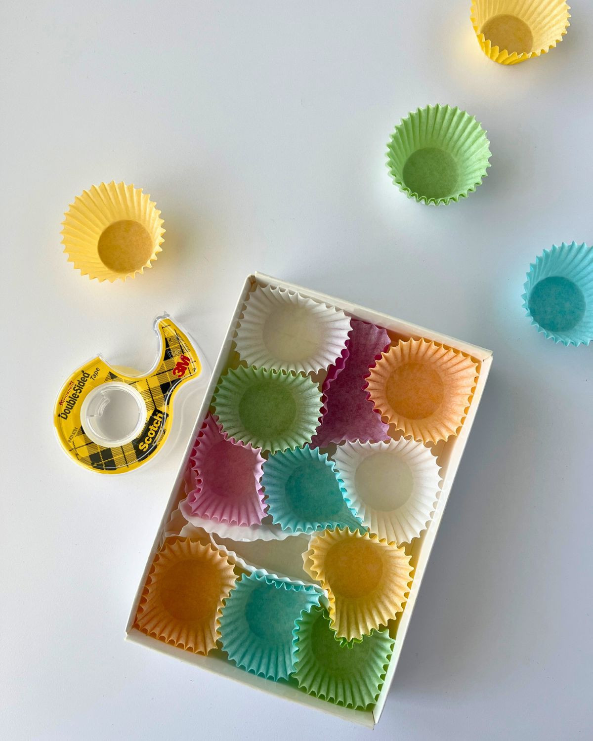 Securing paper liners into an empty candy box using tape for a DIY money gift box