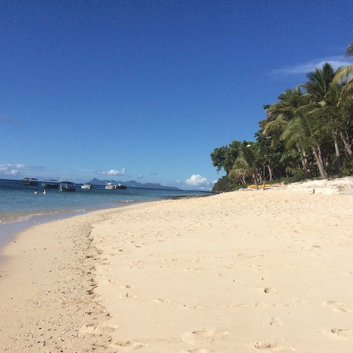 Serene beach in Fiji with clear turquoise water and white sand, representing the inspiration for natural gift hamper ideas.