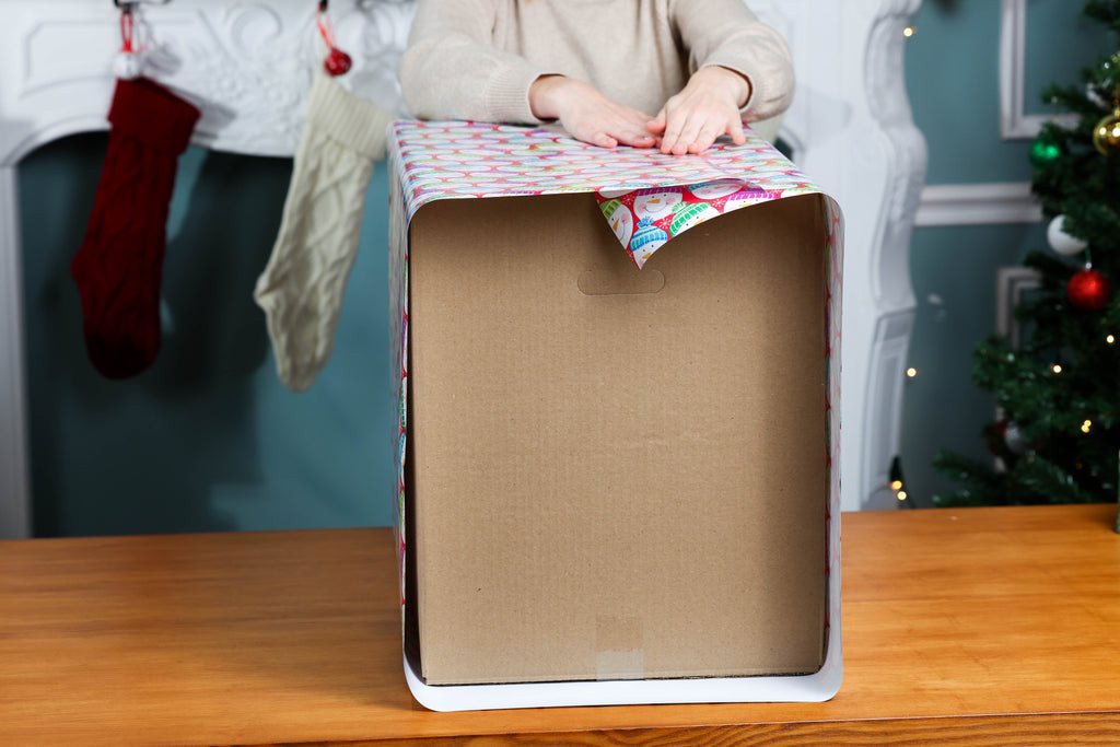 Folding the sides of the wrapping paper to address gaps in coverage on the large box.