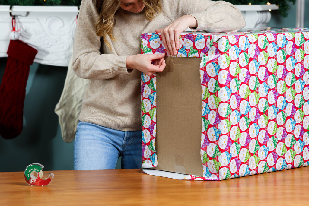 Folding and taping the ends of the wrapping paper for a secure and neat finish on the large box.