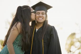 Girl kissing sister on cheek at graduation