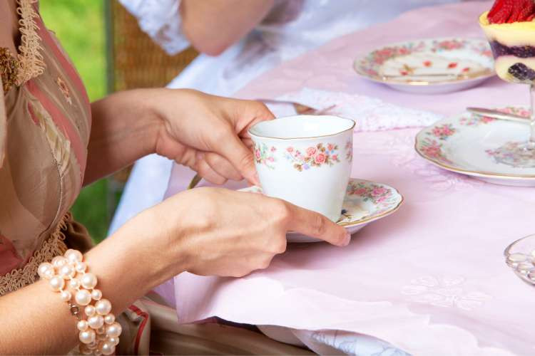 woman holding teacup at afternoon high tea party
