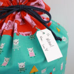 Plain paper gift tags attached to drawstring bags