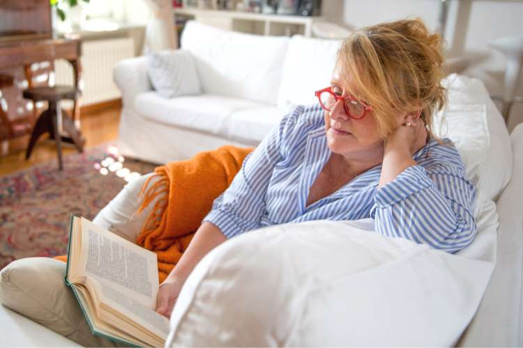 woman reading book on couch