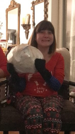 Hands holding a saran wrap ball filled with gifts