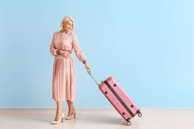 woman in pink dress carrying matching pink luggage